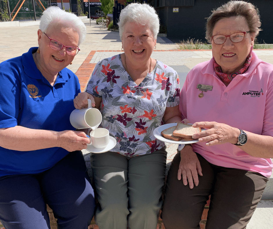 Three ladies sitting together with the Devonport Mayor Annette Rockliff in the middle pretending to serve them breakfast. The photo is to promote the Devonport volunteers breakfast being held on Monday 6 December.
