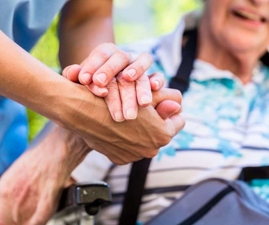 a carer and person holding hands