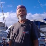 Peter Keating wearing a t-shirt standing in front of yachts and boats in a marina