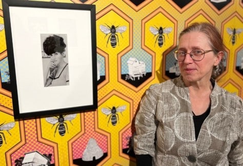 A woman standing in front of a portrait of the Zanny Begg exhibtion.