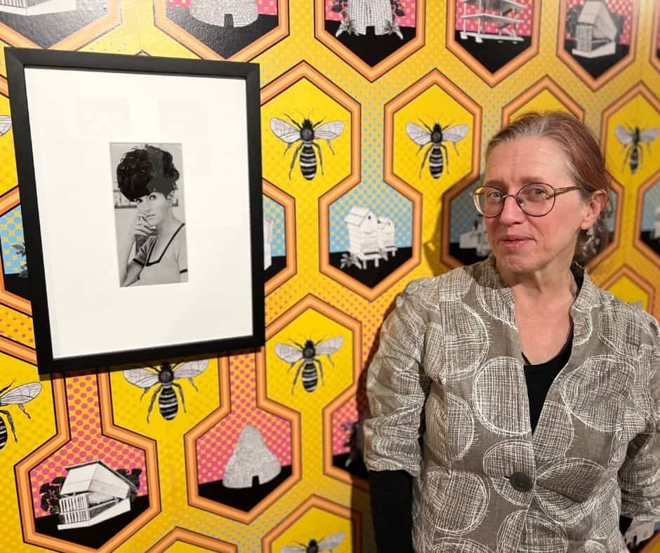A woman standing in front of a portrait of the Zanny Begg exhibtion.