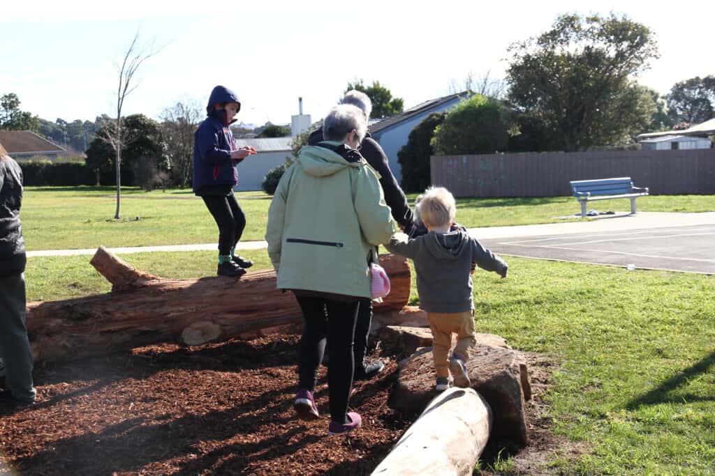 Children balance on logs surrounding a nature playground