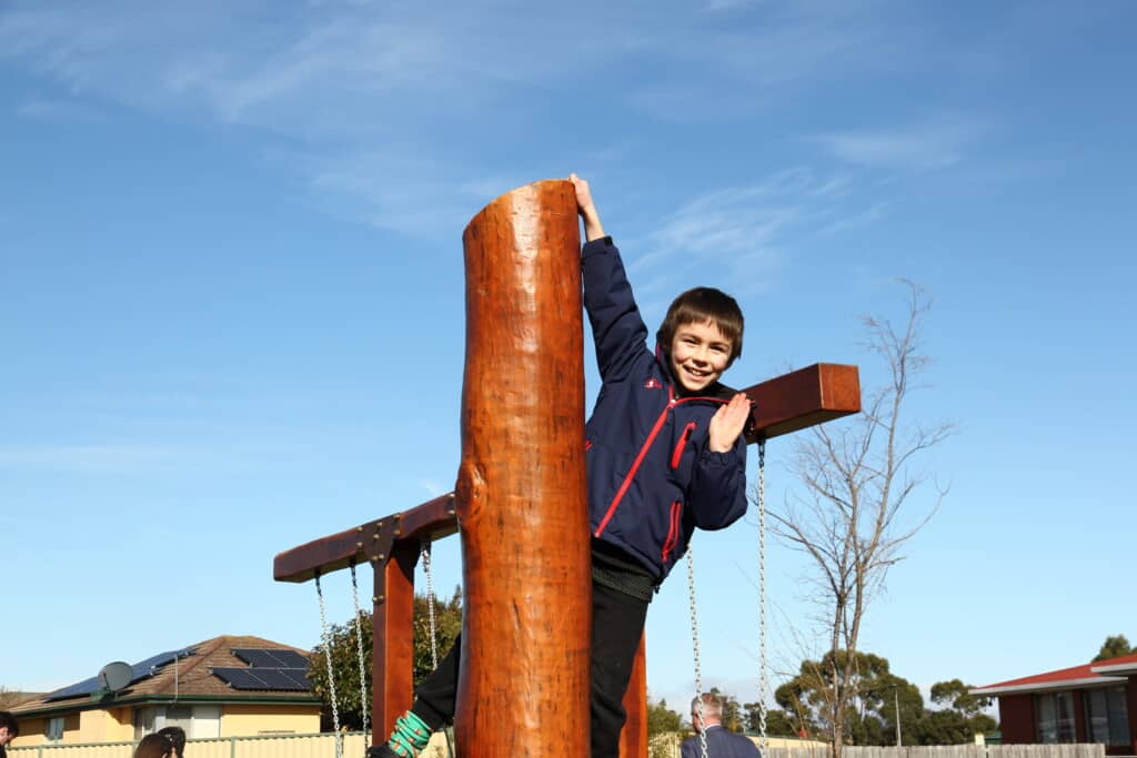 A child waves from a height on a climbing pole