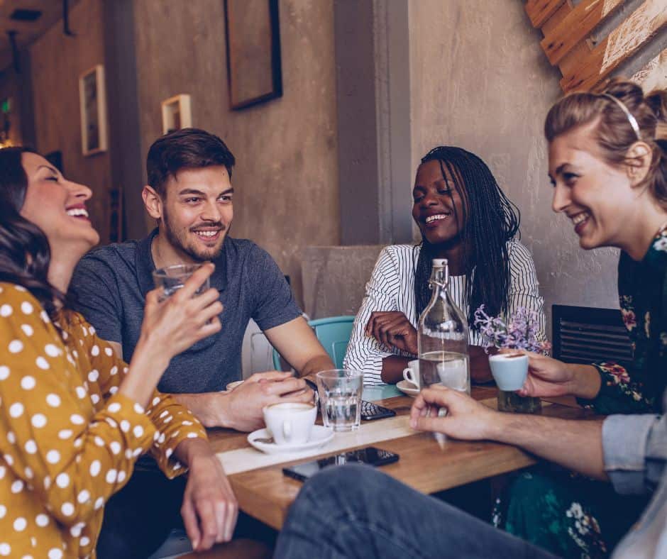 A group of friends around a table in a venue, they all have smiles and there are drinks on the table