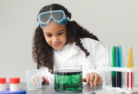 A Child Scientist is cooking up something colourful in a beaker