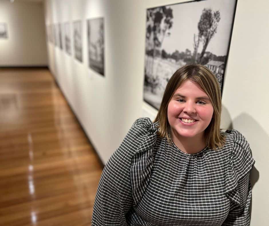A young woman stands in front of old photographs in the Devonport Regional Gallery.