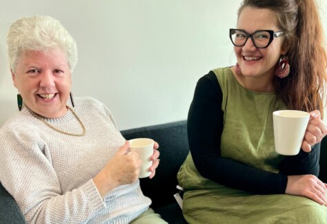 Two women sitting next to each other having a cup of tea, to promote this year's Seniors' Week.