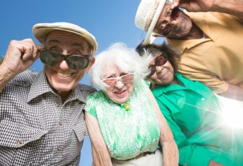Elderly people wearing sunglasses looking down at the lens.