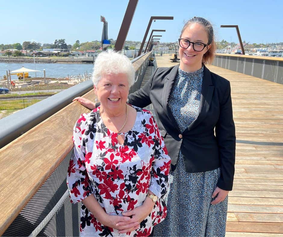 Two women standing next to each other on the elevated walkway in Devonport. The two women are Devonport Mayor Annette Rockliff and Novotel Devonport General Manager Ana Royal overlook the new waterfront park, where the Tasmanian Symphony Orchestra will hold a free concert called Symphony on the Waterfront next year.
